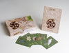 The Māori Oracle by Schiffer Publishing, Ltd. is shown with its box, guidebook, and five fanned-out cards, each displaying unique designs inspired by Māori culture and nature for spiritual guidance in New Zealand.