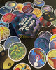 A hexagonal box labeled Wild Harmonic Oracle Cards from Schiffer Publishing, Ltd. is surrounded by vibrant chakra cards with abstract designs, each inspired by energy alchemy and spread out in a colorful fan shape.
