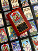A red box labeled The Buddha Tarot by Schiffer Publishing, Ltd. rests on vibrant tarot cards, each adorned with Buddhist-inspired art, Major Arcana themes, and symbols reflecting the journey to enlightenment.