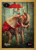 A woman in blue with a feathered hat sits on a decorated elephant under a red umbrella in an enchanted forest. The Rider card from the "Lenormand of Enchantment" by Schiffer Publishing, Ltd. is ideal for tarot readings or guidebook reference.