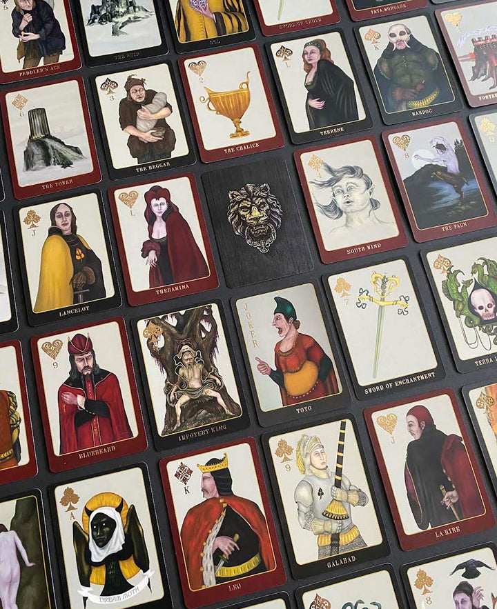 A tabletop displays The Doors of Somlipith by Schiffer Publishing, Ltd., a set of illustrated playing cards featuring unique fantasy artwork and mystical names, evoking the tradition of esoteric tarot and magical card readings.