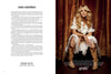 Country singer Carrie Underwood sits on a wooden chair in a white dress and cowboy boots, wearing a Milk Mustache from Schiffer Publishing, Ltd., with rustic curtains hanging behind her.