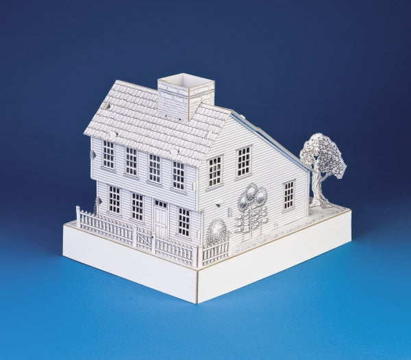 The Saltbox House by Schiffer Publishing is a detailed white paper model featuring a chimney, picket fence, and trees, set against a blue background—ideal as an activity playset for creative minds.