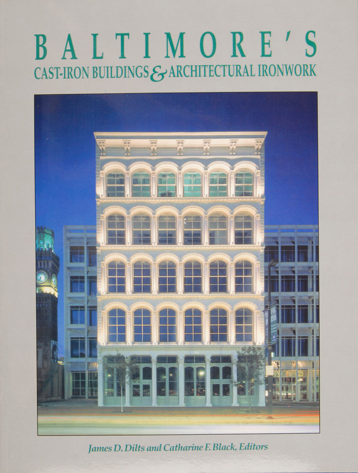 The cover of Baltimore's Cast-Iron Buildings & Architectural Ironwork by Schiffer Publishing displays a well-lit, cast-iron masterpiece at night with columns and arched windows; editors’ names are featured at the bottom.