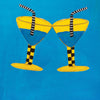 Two yellow cocktail glasses with blue liquid and striped straws clink on a blue background. Their checkered stems echo the bold style of the Outsider Art Tarot by Schiffer Publishing, Ltd. Text below: LOVE TWO OF CUPS.